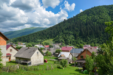 Fototapeta na wymiar Colorful summer rural landscape with houses in the valley and mountains on background. Lifestyle in the Carpathian village Kolochava. Carpathians, Ukraine