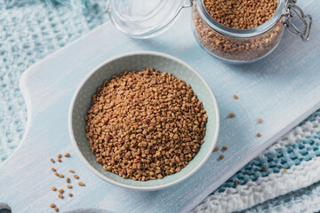 Bowl of fenugreek dry seeds on light blue background. Healthy food, Ayurveda and alternative medicine concept
