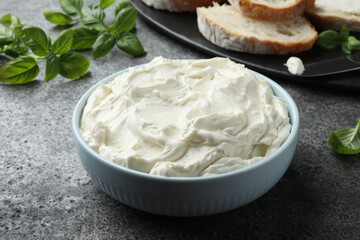 Tasty cream cheese and basil on grey table