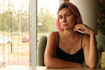 A young stylish woman is bored in a cafe.