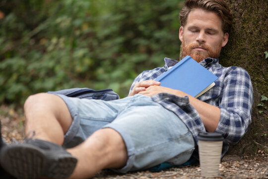 young man with book resting in comfortable outdoors