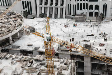 Сonstruction crane works. Construction workers are building a high-rise building. Building materials and construction equipment
