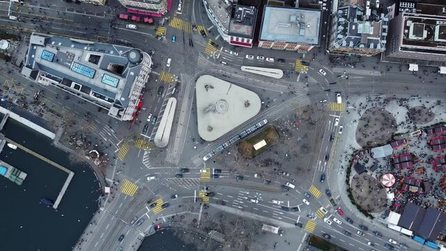 Aerial top down of the traffic on the Bellevue intersection in Zurich city center by the Limmat river with tramways, cars and buses in Switzerland largest city. Shot with a rotation motion
