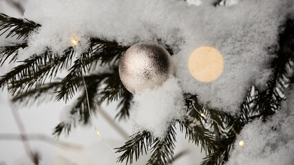 holiday long banner. beautiful golden Christmas decoration on a snow-covered branch of a Christmas tree and a beautiful garland with yellow lights. selective soft focus