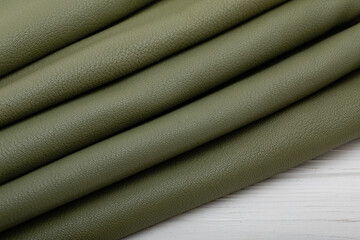 Fototapeta premium khaki green folded natural textured cow leather on the wooden table 