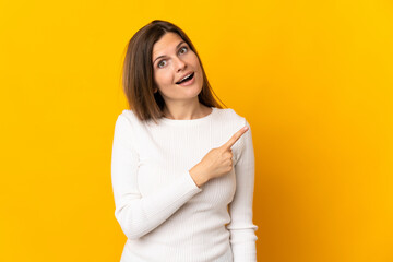 Fototapeta premium Young Slovak woman isolated on yellow background surprised and pointing side