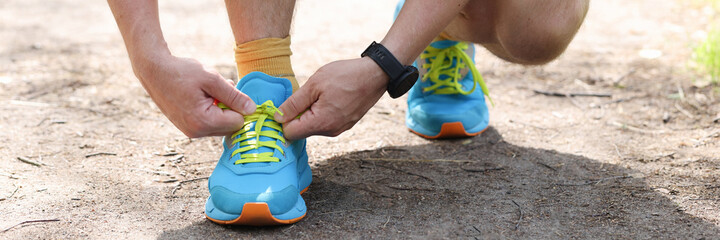 Man shoelaces laces on sports fashion sneakers in park