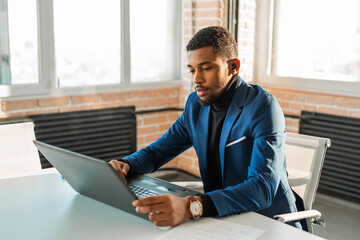 handsome adult african man at table with laptop at work