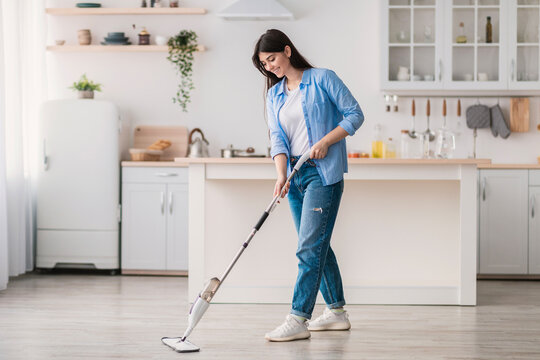 Portrait of woman cleaning floor in kitchen with spray mop