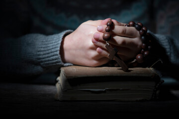 Portrait of young beautiful girl praying to God with rosary. Horizontal image.