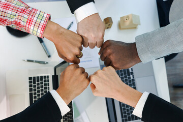 Overhead view of business people putting hands fist join together over meeting desk, partnership...