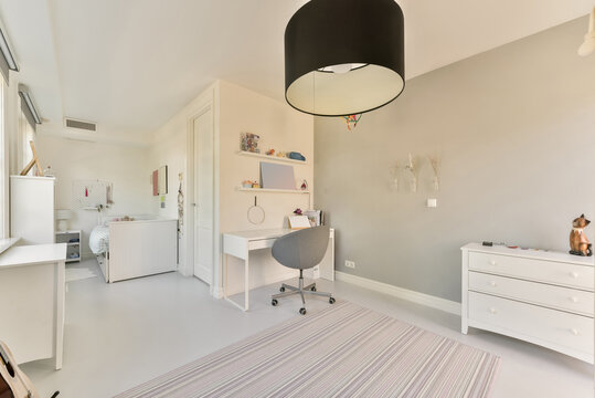 Cozy bed and working zone in light bedroom with white furniture