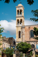 Ein alter und historischer Kirchturm in der Stadt Chania auf der Insel Kreta in Griechenland, davor griechische Flaggen