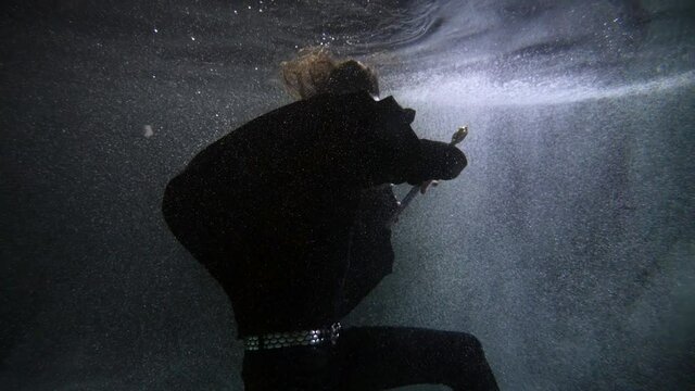 brave medieval knight with sword is sinking in sea, diving underwater, fighting with black magic