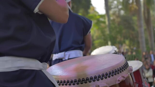 Slow motion closeup focused percussionist playing Japanese drums on stage during concert 
