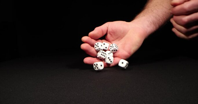Rolling White dice on a black background. Hand dropping dice. Macro shot, side-view camera tracking. 4k
