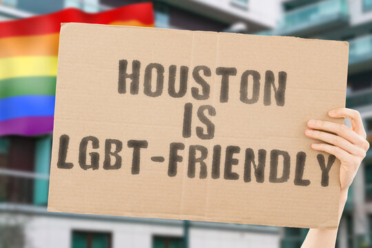 The phrase " Houston is LGBT-Friendly " on a banner in men's hand with blurred LGBT flag on the background. Human relationships. different. Diverse. liberty. Sexuality. Social issues. Society