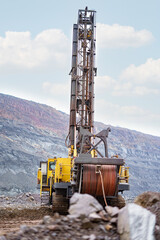 Large drill rig in an ore quarry. Preparation of boreholes for laying explosives in the quarry. Open-pit mining technologies.