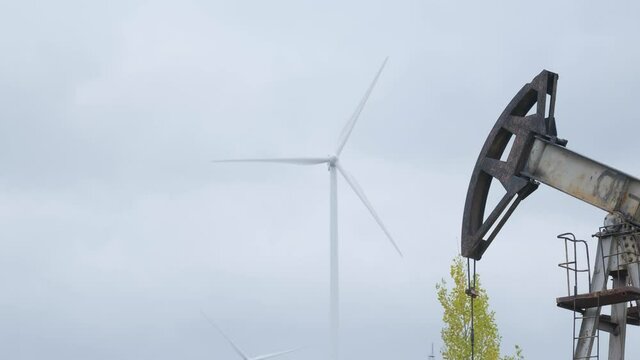 Oil pumps in work with electric windmill on background