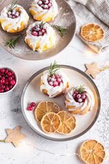 lemon cupcakes decorated with cranberries and icing on a light gray background. christmas lemon cupcakes.
