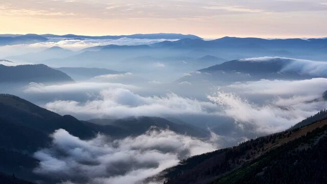 Clouds spill over the tops of the hills in the light of the rising sun, Mystical Atmosphere