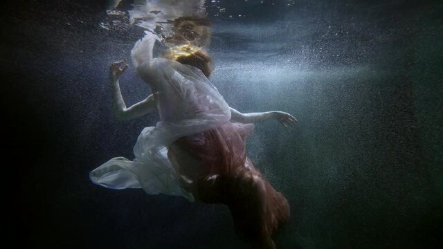 underwater shot with amazing beautiful young woman in silk flowing dress, grace and beauty