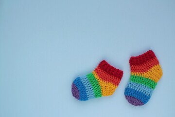Rainbow bright striped socks on blue background. Newborn gift. Handmade crochet booties
