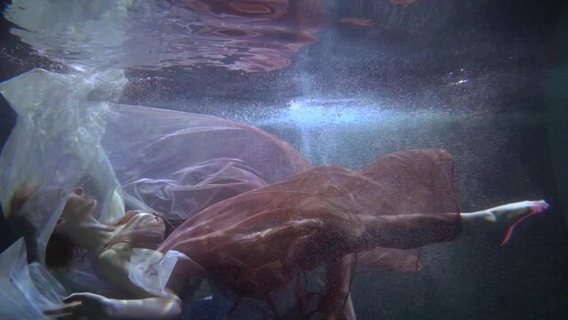 romantic subaquatic shot with floating in water woman, graceful lady is swimming underwater