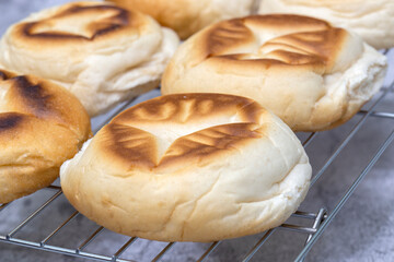 Freshly baked English muffins cooling on a metal rack.  On a concrete background