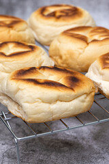 Freshly baked English muffins cooling on a metal rack.  On a concrete background