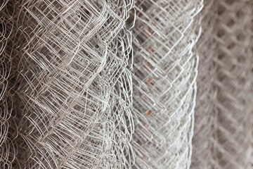 Metal mesh netting rolled into rolls. Rolled chain-link fence.