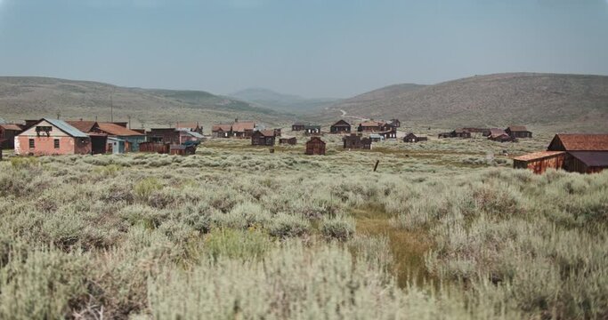 Wide dolly shot of an old gold rush, mining, ghost town in the desert of California