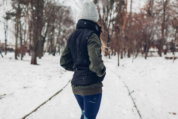 Runner ready for training in snowy winter park. Woman working out outdoors. Sportive lifestyle