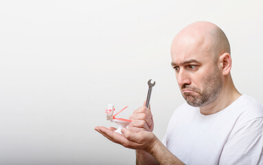 confused bald man with toy water closet and spanner