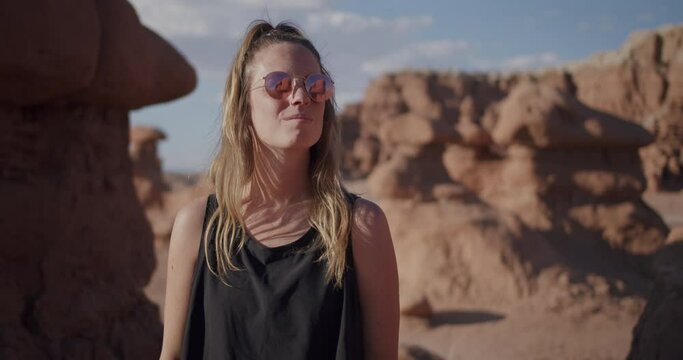 Attractive girl model with retro sunglasses looking around at the rock formations in Goblin Valley State Park in the desert of Utah