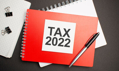 Tax 2022 sign on sheet of paper on the red notepad with pen