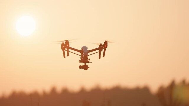 At sunset flying quadcopter drone scanning agricultural landscape harvest crops vehicle aircraft. Computer analyze. Innovation technology. Smart farming.