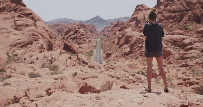 Young female photographer takes a picture of a long straight road in valley of fire state park in Nevada