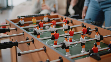 Close up of colleagues playing at foosball table after work. Workmates using board to play football...