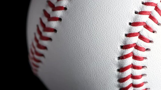 Close up of rotating baseball with black background.