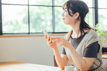 カフェでスマホを使う女性（見る）
