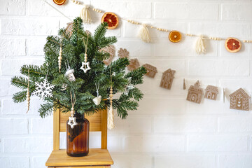 Brown glass jar with fir branches stands on a wooden chair. Zero waste christmas concept.