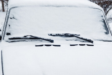 Car windshield wipers and windscreen in snow, closeup