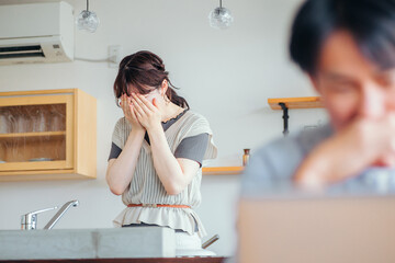 辛い思いをする女性とパソコンを使う男性
