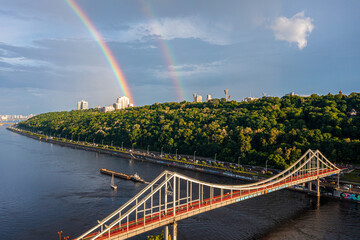 Fototapeta na wymiar Panoramic view of Kyiv city with a beautiful rainbow over the city. Aerial view of the Arch of Friendship of Peoples.