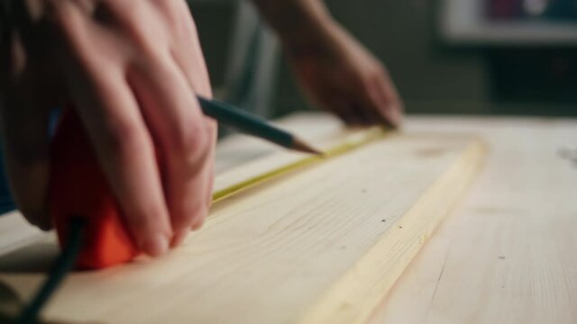 Woman builder using roulette wheel and drawing mark on wooden board close-up. Making diy furniture. Renovation concept. Building new house or flat.