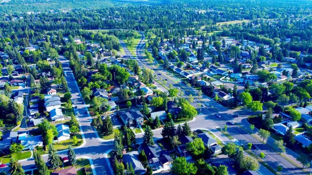 Edmonton Summer Aerial over 87th Ave NW on a clear sunny day flyover residential detached MLS prime realty properties at identifying altitudes towards Hawrelak Park lush green forest foliage Canada