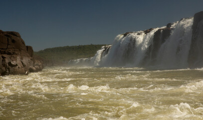 Navigating the rapids. The majestic Mocona falls seen from the boat. The rocky waterfall white water, strong river current flowing across the jungle.