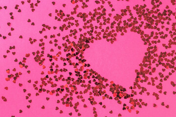 A creative heart made of a large number of small shiny hearts on a pink background. The concept of Valentine's Day.