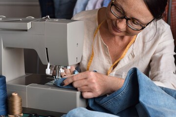 Seamstress using sewing machine for hemming jeans